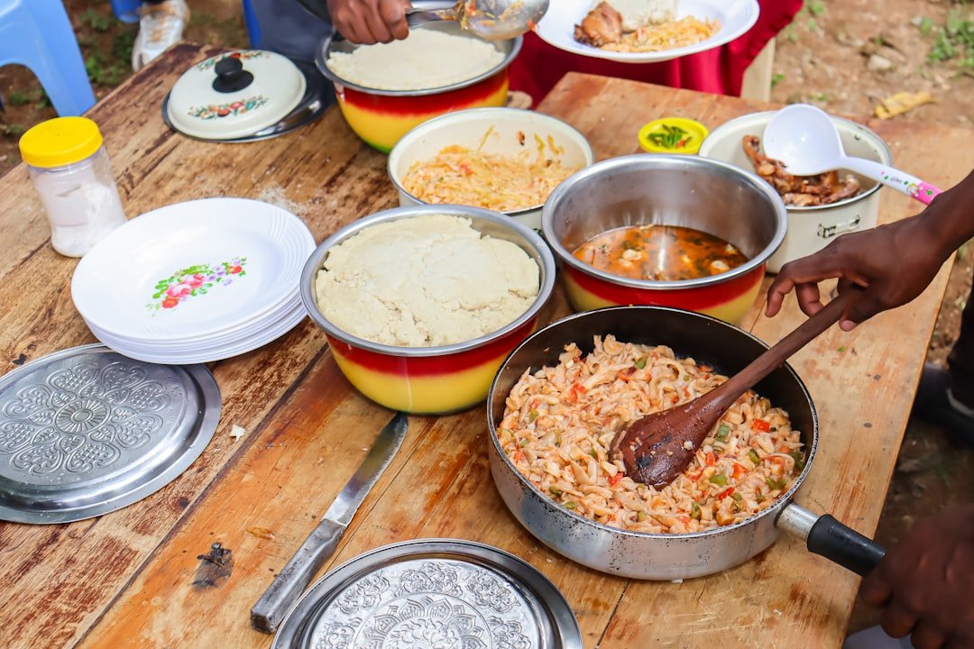 Fresh ingredients for Kenyan irio laid out on a wooden table: potatoes, green peas, maize, and sukuma wiki