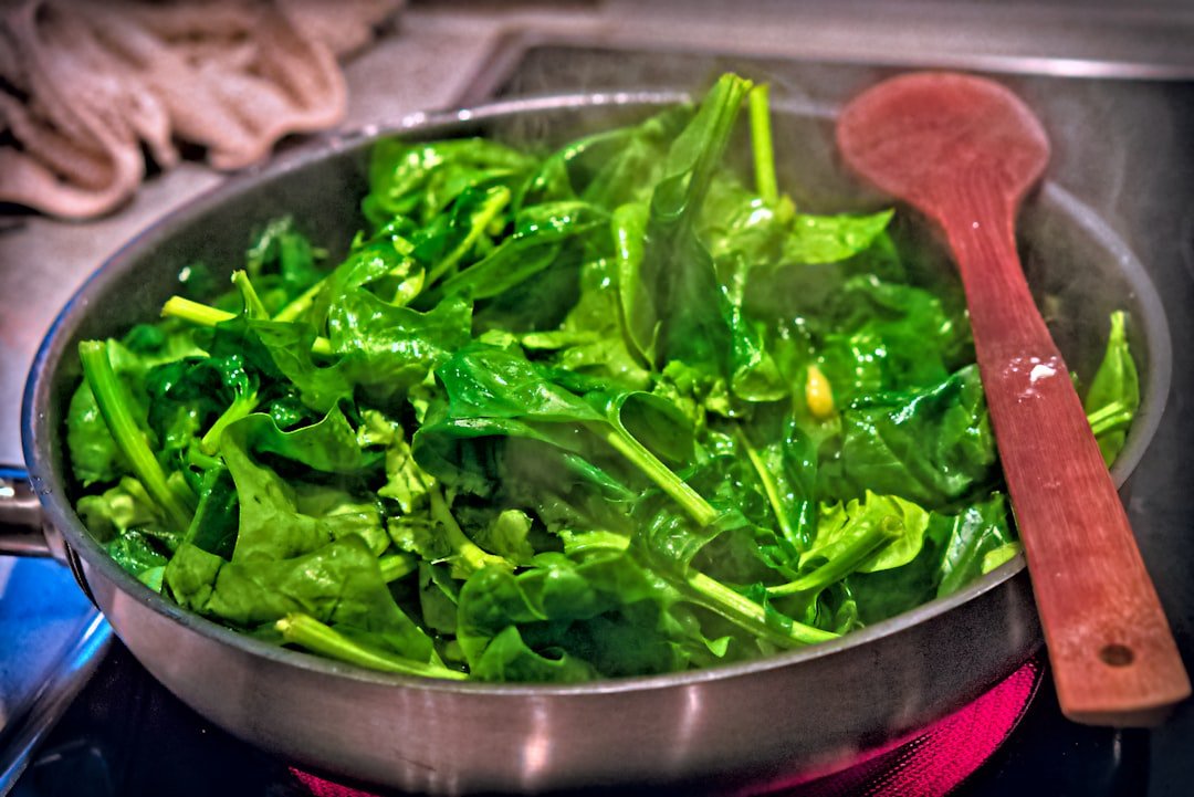 Pan of green African leafy vegetables cooking on a stove — kenyan traditional greens