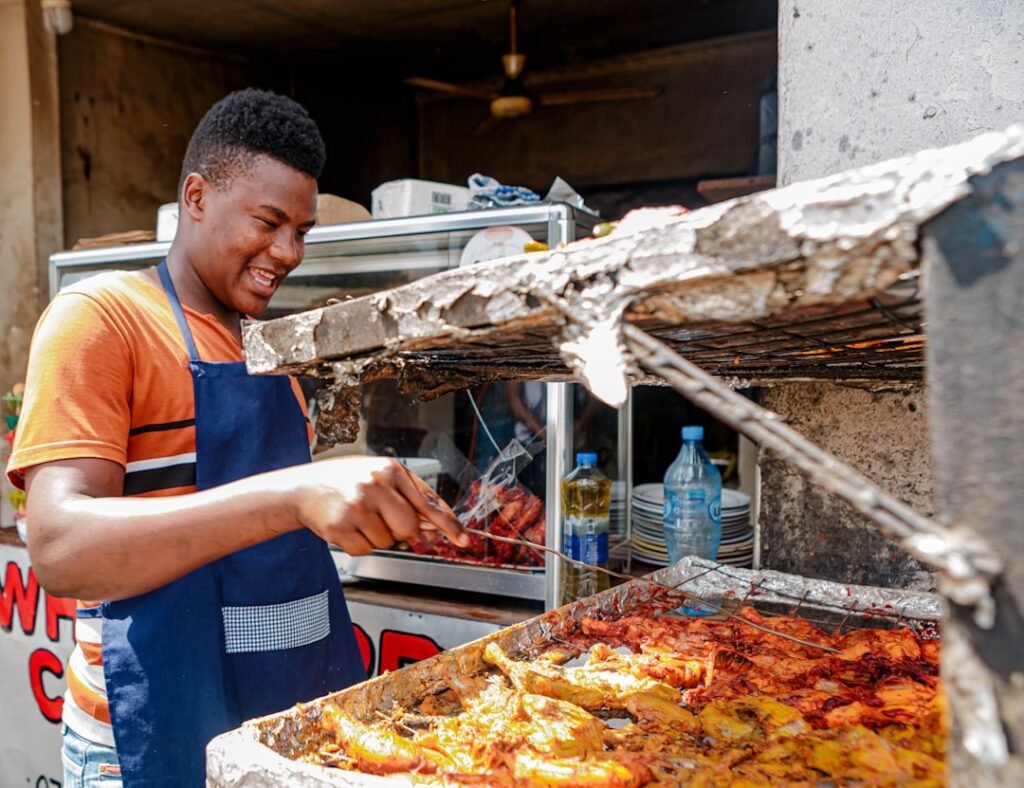 Street food vendor grilling smokie sausages over charcoal in Nairobi, Kenya