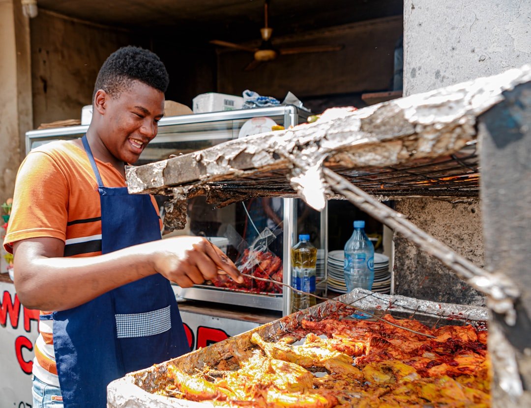 Street food vendor grilling smokie sausages over charcoal in Nairobi, Kenya