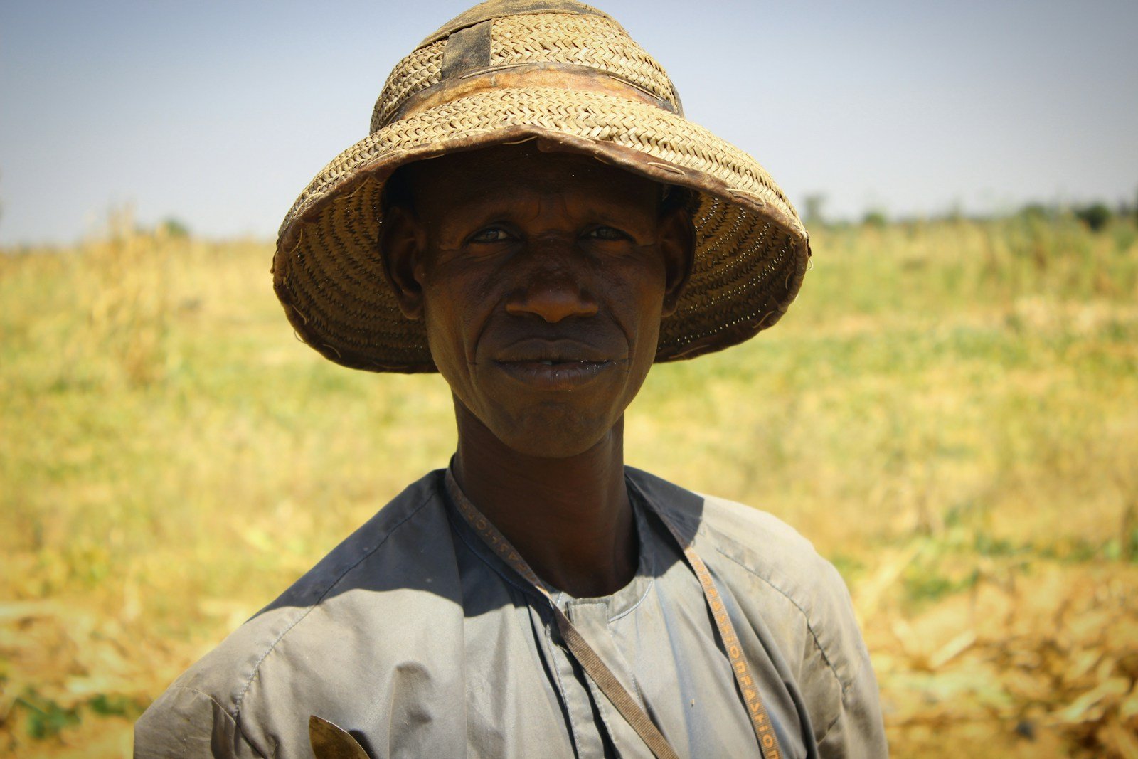 Smallholder farmer in Kenyan highlands tending crops near a macadamia orchard