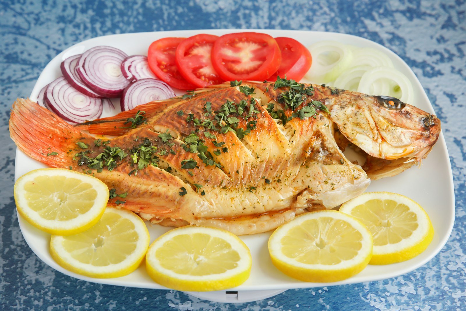 Whole tilapia fish on a plate with lemon — Kisumu food guide Lake Victoria fish